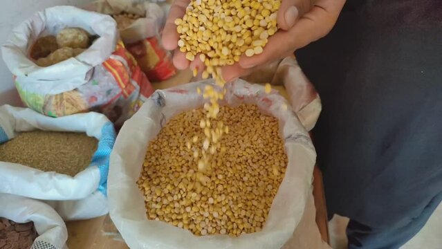 Close-up shot of a man's hand, pile of raw chickpeas dal in hand, man throwing chickpeas dal down by hand. Hand falling chickpeas dal on background. Beautiful slow motion 4K footage.