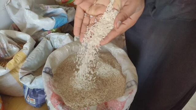 Close-up shot of a man's hand, pile of raw rice in hand, man throwing rice down by hand. Hand falling rice on background. Raw split dried rice. Beautiful slow motion 4K footage. 