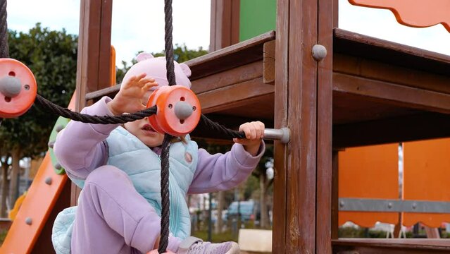 Happy child on the playground. Climbing around the structure
