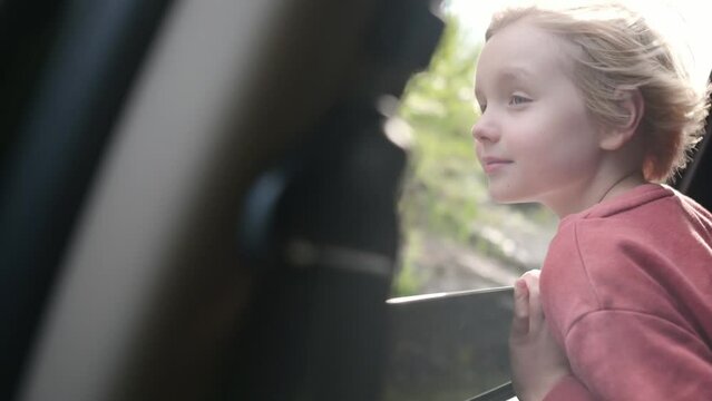 Preteen boy look out through window of car during family road trip and enjoy of pleasant expectation of happy vacation. Glad child travel with parents while holidays. Journey through the countryside