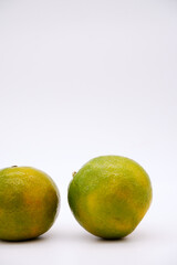 Tangerine oranges are placed on a white background. Two orange with green skin of still-life food concept with a white background. Orange fruit with copy space for freshness and healthy eating.