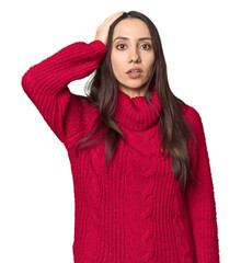 Young Caucasian woman in cozy red sweater on studio background being shocked, she has remembered...