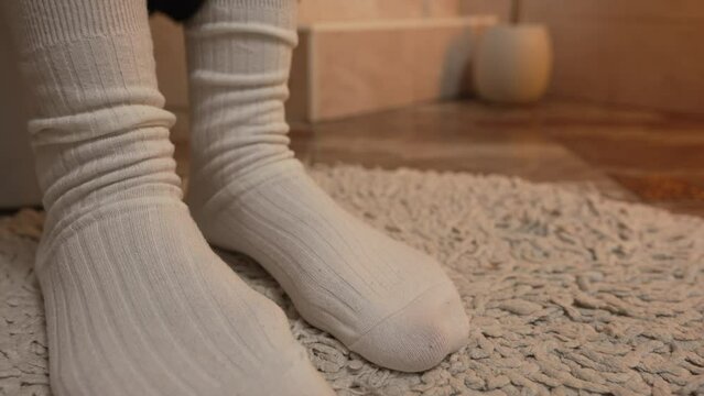 Close-up legs in warm white socks in the toilet hands puts on panties