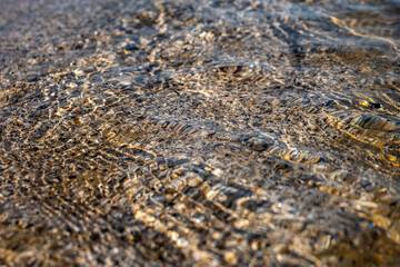 Crystal clear sea water texture with glare from the sun, wallpaper