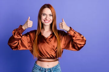 Gordijnen Portrait of nice young woman show thumb up empty space wear brown shirt isolated on purple color background © deagreez