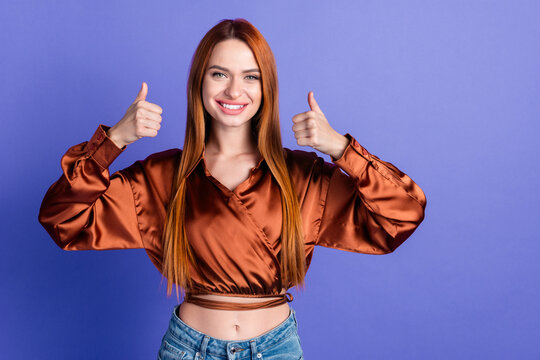 Fototapeta Portrait of nice young woman show thumb up empty space wear brown shirt isolated on purple color background