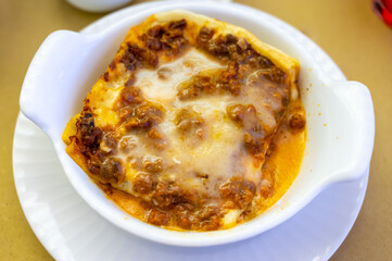 Traditional first course for lunch or dinner in Italy, lasagne Bolognese with beef meat and bechamel sauce served in Italian restaurant, Milan, Italy