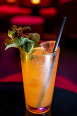 Whiskey and rum colorful cocktails served with ice cubes on black table in dark cocktail bar in Italy