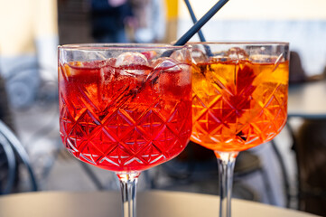 Aperol and Campari Spritz orange bitter long drink cocktails made with liqueur, prosecco sparkling wine, ice cubes and piece of orange, Milan, Italy