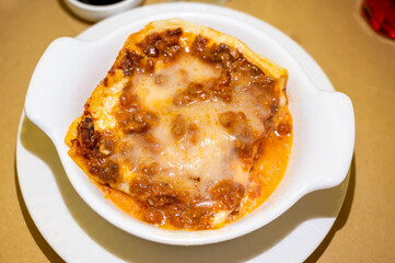 Traditional first course for lunch or dinner in Italy, lasagne Bolognese with beef meat and bechamel sauce served in Italian restaurant, Milan, Italy