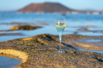 A glass of champagne or cava on vacation, low tide on Dunes Corralejo sandy beach, Fuerteventura,...