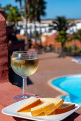 Spanish hard manchego, cow, sheep and goat cheese, cold white wine and blue swimming pool on background