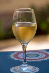 Glass of cold white wine on white terrace table outdoor in sunny day