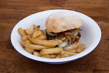 Sandwich. Closeup view of a crispy fried chicken sandwich with bacon, cucumber and french fries in...