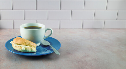 Coffee in white porcelain cup on blue plate with bagel and cream cheese