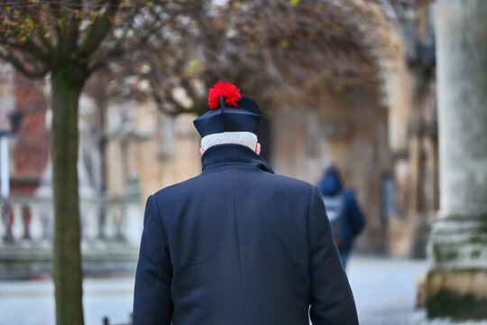 Ksiądz katolicki w birecie z czerwonym pomponem. 