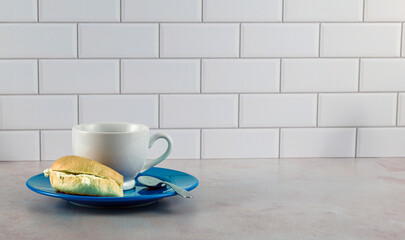 Coffee in white porcelain cup on blue plate with bagel and cream cheese