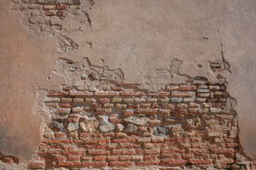 Old broken stucco revealing brick wall underneath
