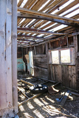 Interior of abandoned train car in shambles. Wooden frame with sunlight and shadows.  Trash filled abandoned structure. 