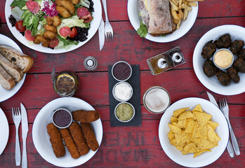 Top view of the restaurant table with drinks and many gourmet dishes such as a chicken sandwich,...