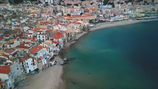 Aerial view of Cefalu, Sicily. Cinematic drone shot of famous travel destination of Italy. Slow drone shot travelling forward and panning down toward the Spiaggia di Cefalu beach