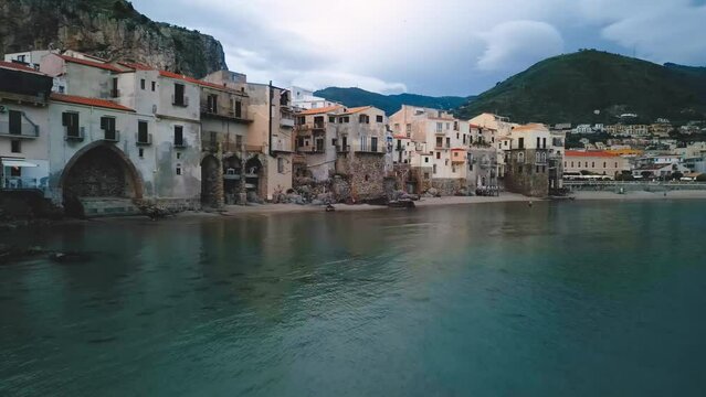 Aerial view of Cefalu, Sicily. Cinematic drone shot of famous travel destination of Italy. Slow drone shot travelling forward in a wide orbit at low altitude above the waves