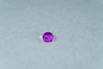 purple water drop looking like a glowing stone on top of white fabric sheet.