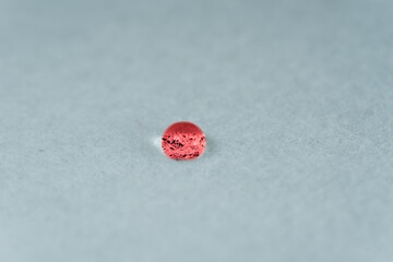 Red drop of water looking like a glowing stone on top of a sheet of white fabric.