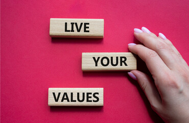 Live your values symbol. Concept words Live your values on wooden blocks. Beautiful red background. Businessman hand. Business and Live your values concept. Copy space.