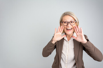 Excited shocked blonde business woman 50s wearing business wardrobe scream news with hands near...