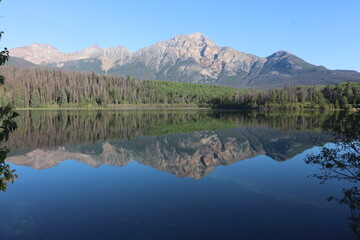 Fototapeta na wymiar Pyramid Mountain reflected in the early morning, still, glass like waters of the stunning Patricia Lake near Jasper in the Canada rockies 