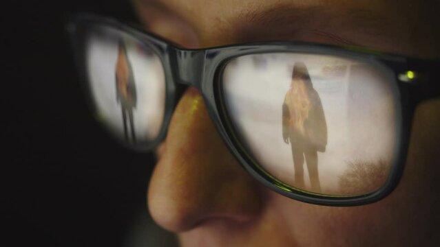 Surfing the Internet and the silhouette of a man burning from within in the reflection of glasses on a female face. Cg