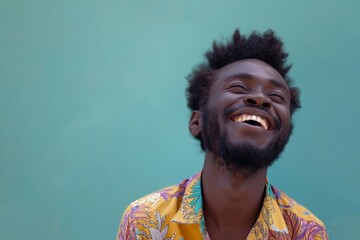 Joyful man laughing against a teal background with copy space