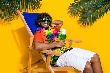 Portrait of carefree cheerful guy wear hawaii shirt drink alcohol cocktail sit on chair at resort...