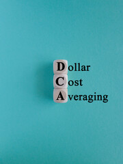 DCA (Dollar Cost Averaging) words on a wooden cubes. Blue background. Saving stock or savings on a...