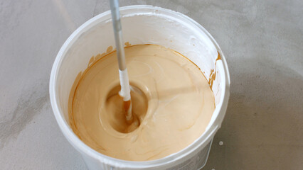 Mixing white and brown paint. Preparation of paint for painting walls.