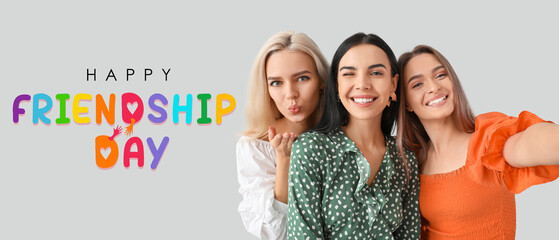 Beautiful young women taking selfie on grey background. Banner for Friendship Day