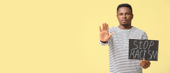 Sad African-American man with poster showing stop gesture on color background. Stop racism
