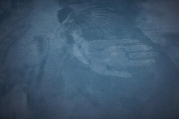 Mark of the hand on the blue velour textured surface. Palm silhouette. Concept of ghostly vision,...