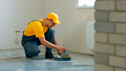 The builder primes the floor. Worker make renovation of apartment.