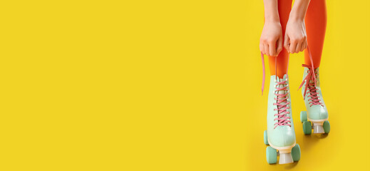 Legs of woman in roller skates on yellow background