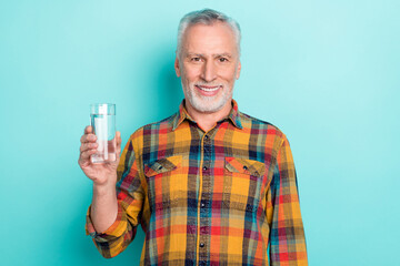 Photo of pretty retired man wear plaid shirt holding water glass isolated turquoise color background