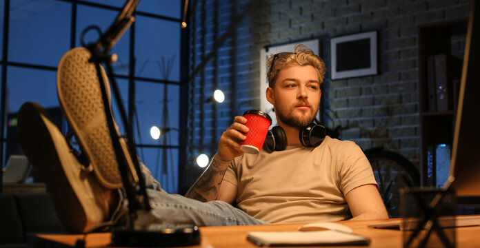 Young man drinking coffee while working late in evening