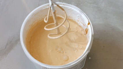 Preparation of paint for painting walls. A mixer and a bucket of paint.