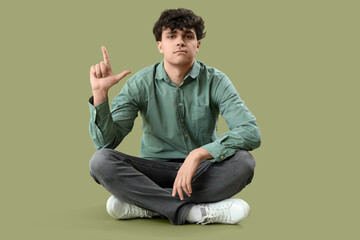 Young man showing loser gesture on green background