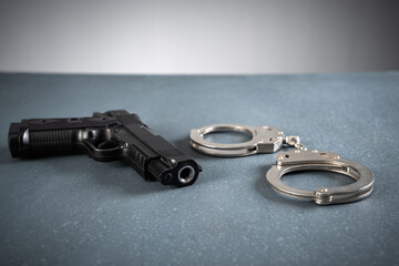Gun and handcuffs on blue background, stock photo, criminal concept - obrazy, fototapety, plakaty