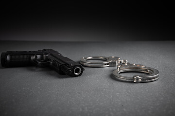 Gun and handcuffs on gray background, stock photo, criminal concept - obrazy, fototapety, plakaty