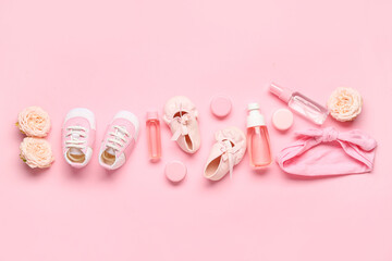 Composition with baby accessories, cosmetics and flowers on pink background