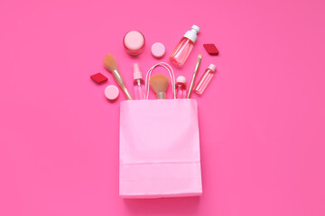 Shopping bag with cosmetic products and makeup accessories on pink background
