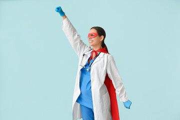 Beautiful female doctor dressed as super hero on blue background